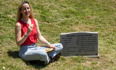 woman sitting near a gravestone holding a cookie