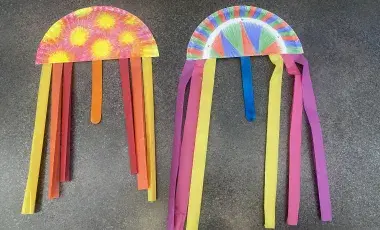 Homemade Guatemalan kites made out of paper plates, tissue paper, and craft sticks.