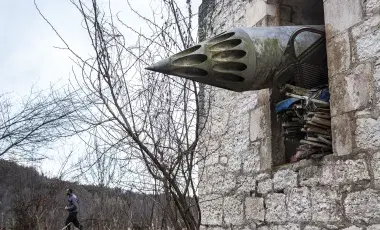 missile protrudes from window of brick building 