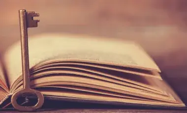 An open book with a skeleton style key before it.