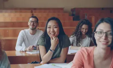 A Group of happy students in a classroom sitting in their seats and enjoying their lesson