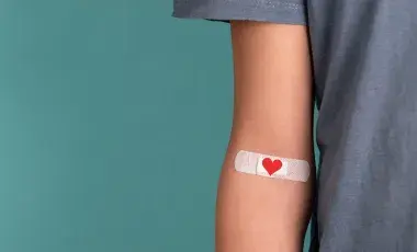 An arm with a heart-themed band-aid affixed 