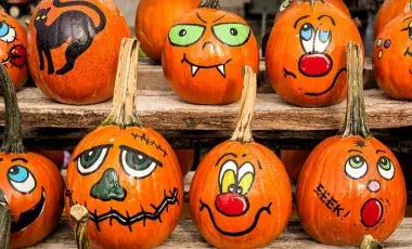 A variety of pumpkins with faces drawn on them. 