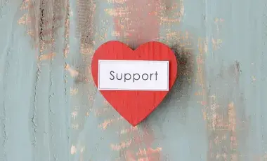 A heart shaped, made of wood with words “SUPPORT”