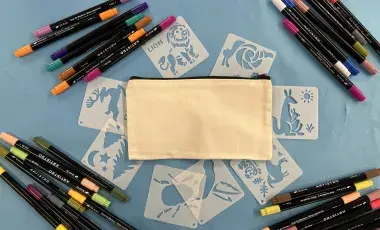 Canvas pouch surrounded by stencils and markers