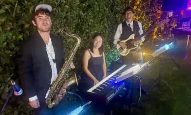 Three musicians with a tenor saxophone, keyboard, and guitar.
