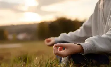 Person meditating in a field.