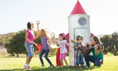 Kids dancing outside with Nathalia playing her guitar