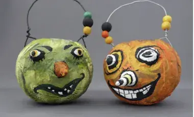 Two paper mache pumpkins posed side by side with spooky smiles.