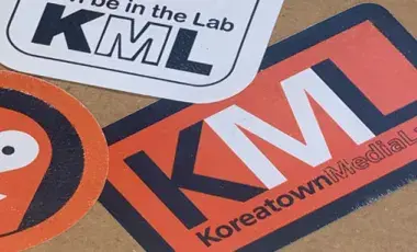 A collection of overlapping Koreatown Media Lab stickers on the back of a school notebook