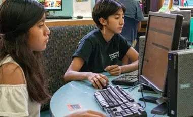 Two young people work on computers.