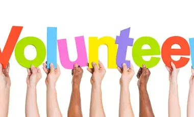 Hands hold up letters spelling "Volunteer"