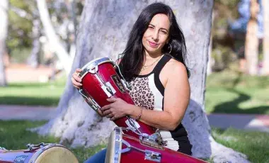 Woman sitting outdoors with three drums