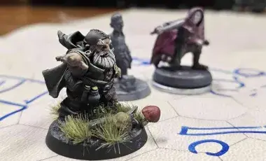 3 painted fantasy character miniatures side by side on a hexagon grid play mat