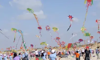 Children fly colorful homemade kites on a beach.