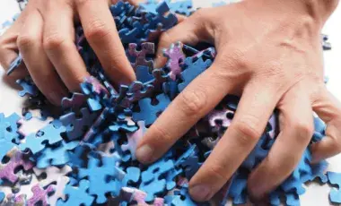 Two hands play with blue and purple puzzle pieces