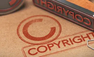 A copyright symbol printed in a piece of brown paper with a metal stamp placed on top.