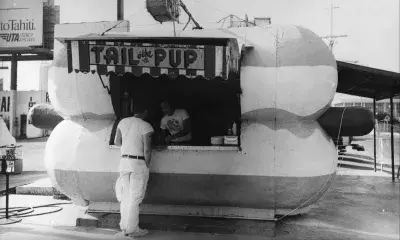 a person orders food from the hot dog-shaped stand