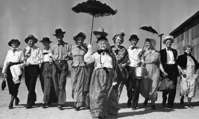 Historic photo of group of people carrying parasols or wearing hats, 1948.