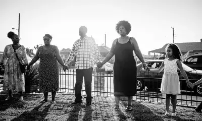 Family of five stands in front yard holding hands in line