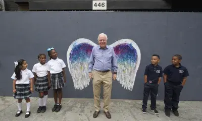Portrait of older adult in front of wings, with several children on either side