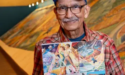 Artist with a photo of a detail from the mural