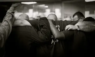 Backs of people standing arm in arm