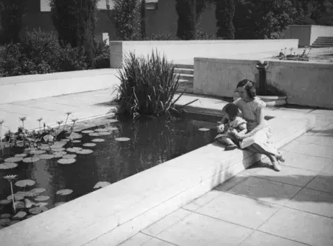 Photo of Woman and Child Sitting By Lily Pond