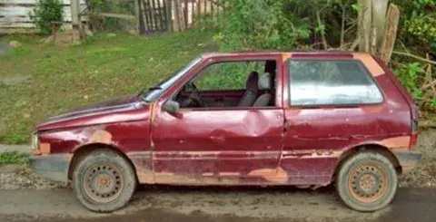 old red compact car in bad shape