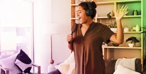 Young person with her headphones and singing into her hair bursh.