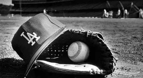 Close-up view of a Dodger player's hat, glove, and ball left on the field