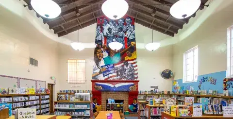 Interior of Angeles Mesa Branch Library with colorful mural called, Education is a Basic Right, over fireplace