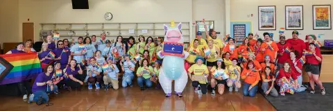 a person in a unicorn costume in front of a group wearing rainbow colored tshirts