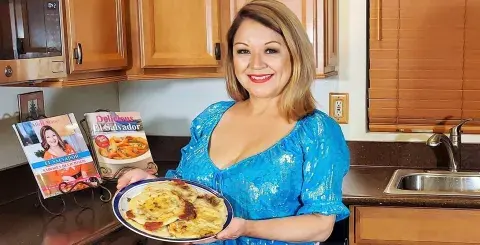 Alicia Maher holding a plate of pupusas in her kitchen