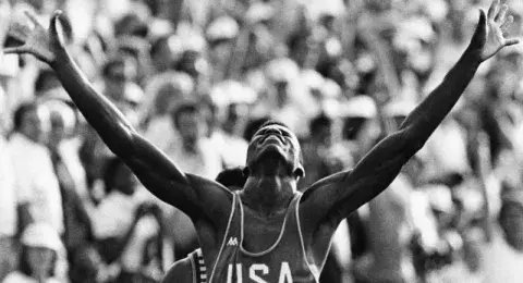 Carl Lewis raises his arms in victory at the LA 84 olympics