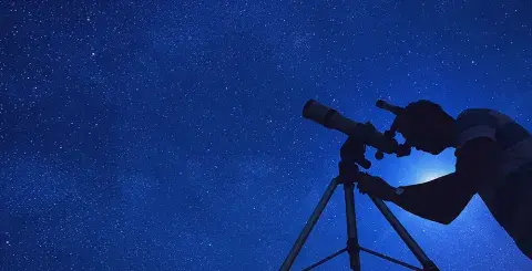 Looking up at the dark, starry night sky with a telescope  