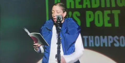 Lynne Thompson reading potery at an event.
