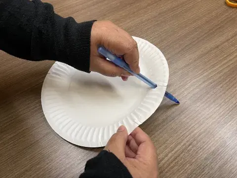 person pokes hole into plate with a pen