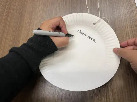 person writes "front door" on paper plate