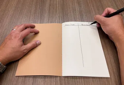 open journal with person writing in two columns