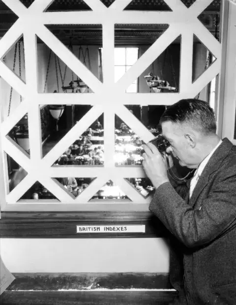 man looking with binoculars through a window