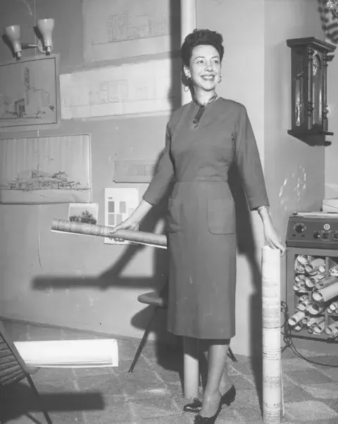 Architect Lucille Raport holding rolled up papers in her hands.