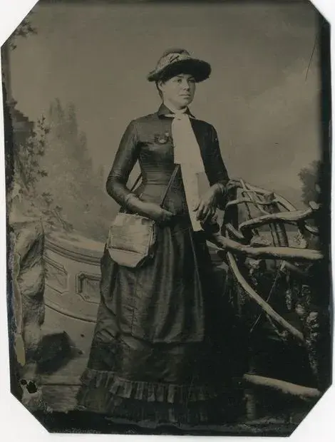 Mary Foy posing in a dress and wearing a hat.