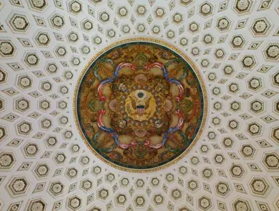 A circular painted mural on the ceiling depicting the Great Seal of the United States.
