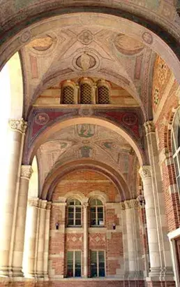 Painted mural on the ceiling of a building's exterior corridor with columns and arches.