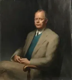 Painted portrait of Julian Ellsworth Garnsey sitting down. He is wearing glasses and dressed in a brown suit.
