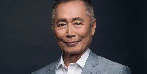 George Takei wearing a gray suit and white collared shirt.