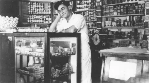 A person behind the counter of the inside of a market.