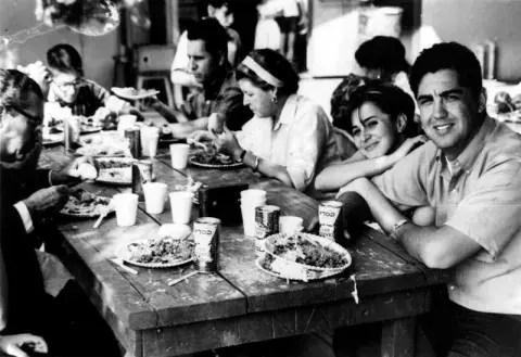 A group of people sitting around a table, having a meal.