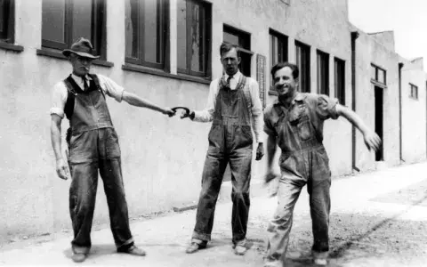 Three men playing with a horseshoe.